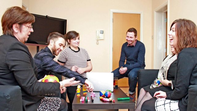 Group of people sat in office looking happy.